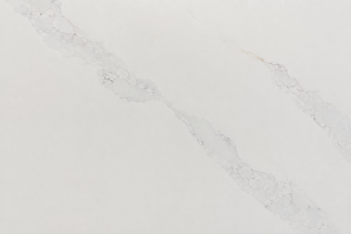 Close-up of white quartz surface with soft gray veining and subtle warm beige accents